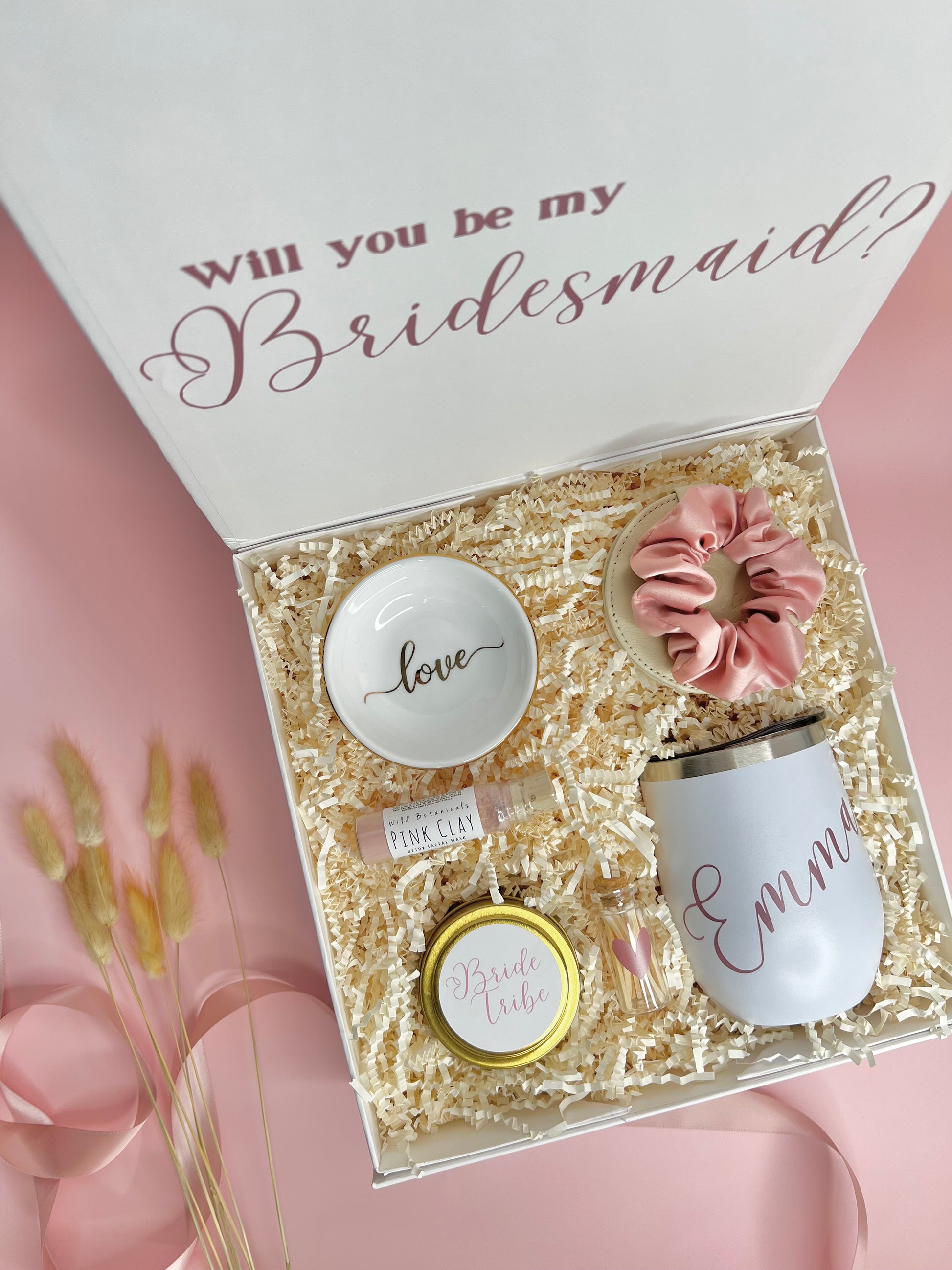 Personalized Bridesmaid Proposal box filled with rose, gold and white products. Contains travel size candle with custom sticker, satin scrunchie, pink clay face mask, compact mirror, ring dish, personalized 12oz tumbler, match jar with striker.